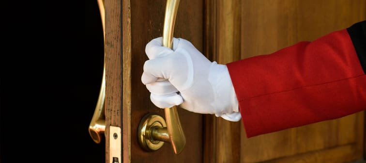 Gloved hand of butler opening ornate door