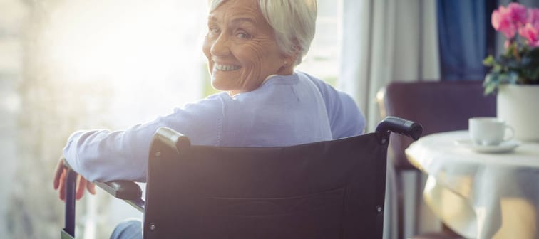 Portrait of smiling senior woman senior woman sitting on wheelchair at home
