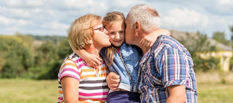 Grandparents giving a kiss to their granddaughter