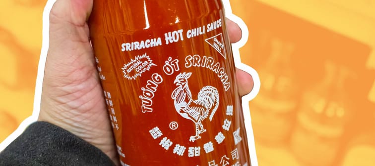 Person holding a bottle of sriracha sauce