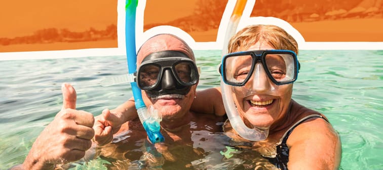 Older couple wearing snorkel gear in in the water, taking a selfie.