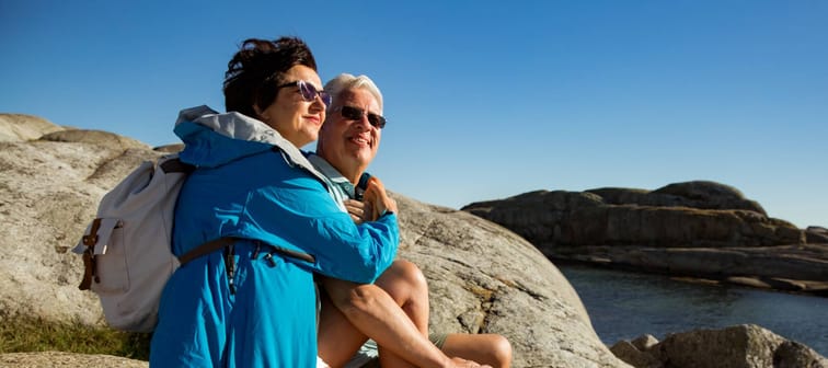 Mature couple sitting on the rocky coastline