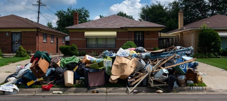 Pile of belongings outside of a run-down looking house.