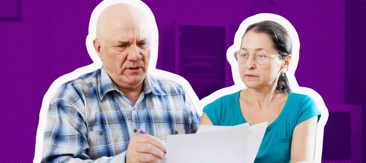 Older couple sitting at a table, looking at papers distressed.