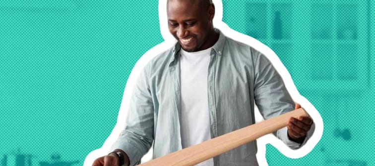 Unpacking new wooden table. Excited african american man ready to assembling desk by yourself after home relocation, standing in kitchen interior and smiling, copy space