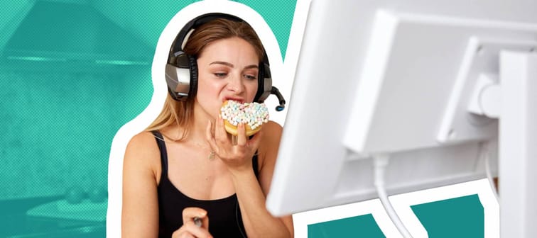 Young woman sits in front of desk at home, biting into a donut.