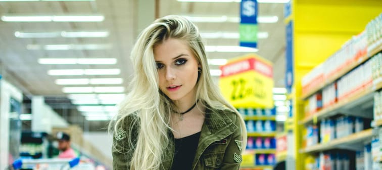 woman looks into camera while crouching on one knee in a shopping aisle