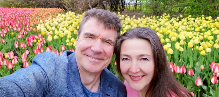 Man and woman smiling in front of tulip garden