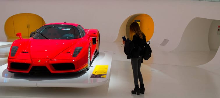 Woman takes photo of luxury red car up close.