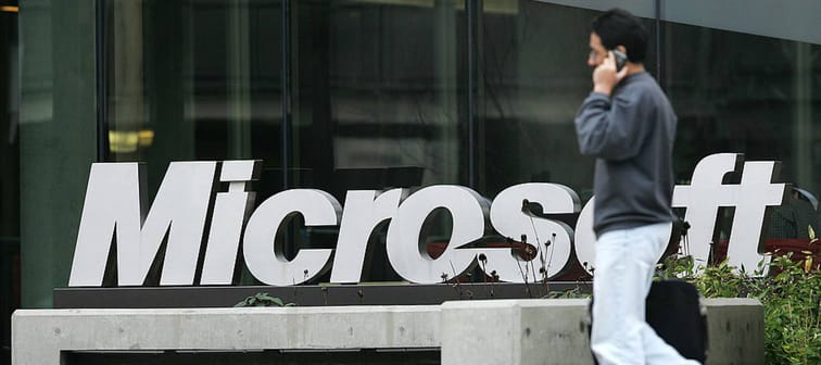 A man on his phone walks by the Microsoft sign outside of an office building.
