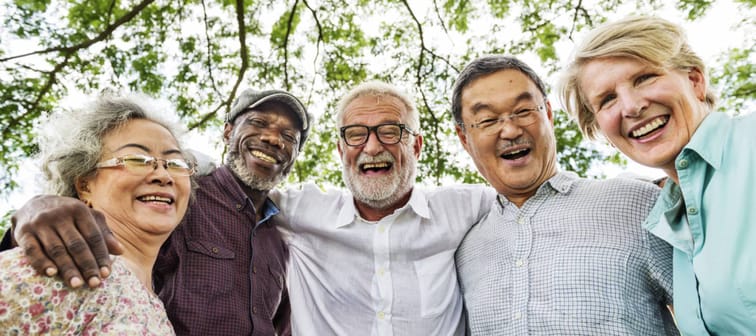 A group of older adults pose smiling with their arms around each other.