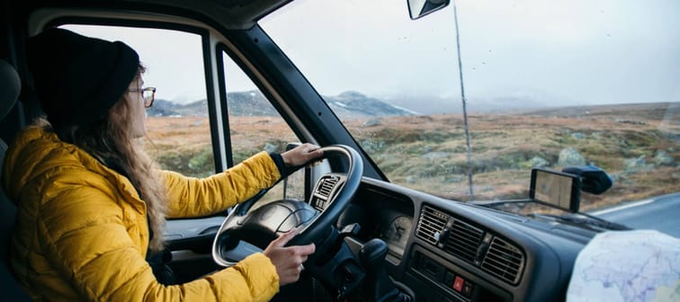 Young woman driving a van on an epic mountain road.