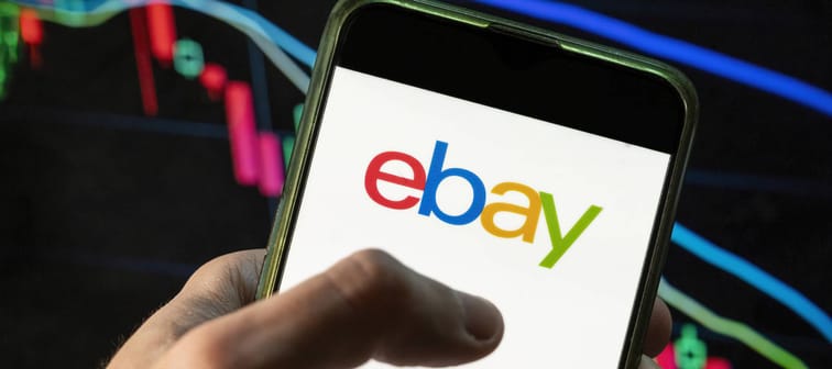 Hand holding smartphone scrolling with eBay logo on screen