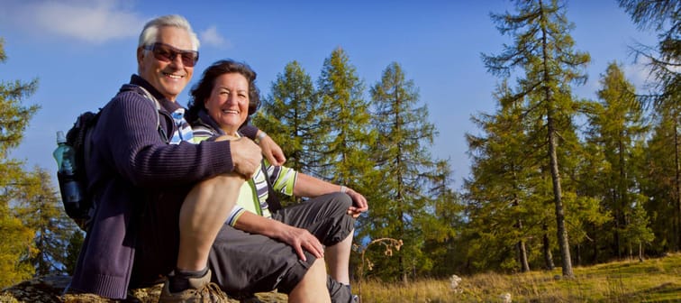 Senior couple pose smiling at camera while hiking.