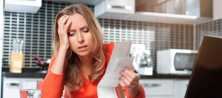 stressed young woman is doing banking and administrative work holding bills at home