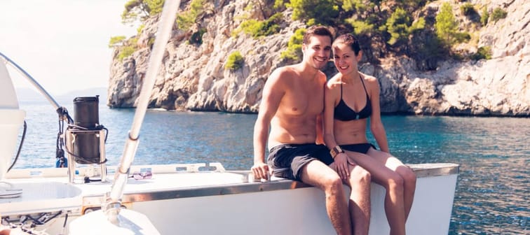 Young attractive couple pose on a boat in a tropical location.