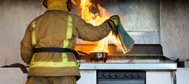 Kitchen fire being put out by a fireman
