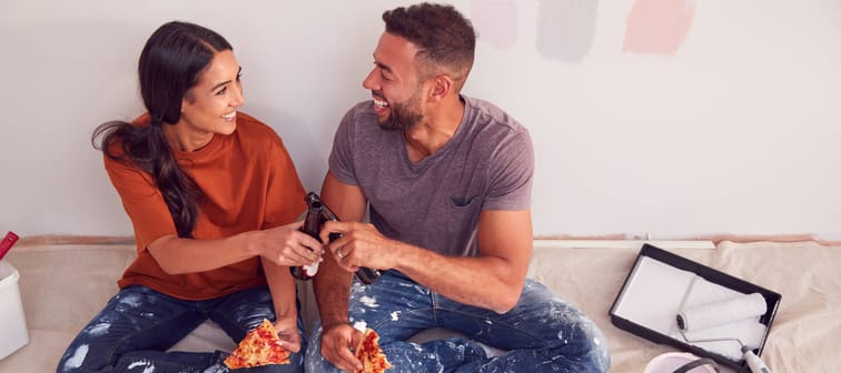 couple taking a break from painting their house, eating pizza