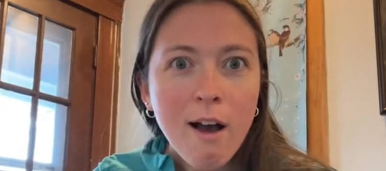Young woman makes shocked face straight to camera.