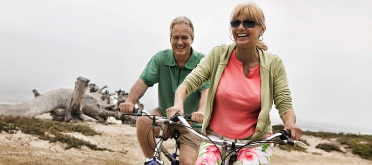 Portrait of middle aged Couple Riding Bikes along Beach