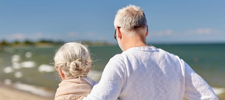 family, age, travel, tourism and people concept - happy senior couple hugging on summer beach