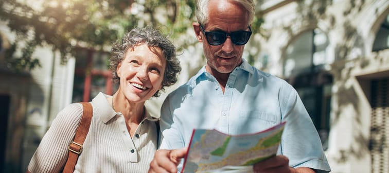 Portrait of senior tourist couple in town using a map. Mature man and woman using map while sightseeing.