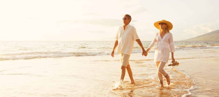 Happy Romantic Middle Aged Couple Enjoying Beautiful Sunset Walk on the Beach. Travel Vacation Retirement Lifestyle Concept