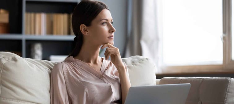 Distracted from work worried young woman sitting on couch with laptop