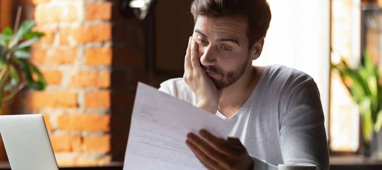 Confused frustrated young man reading letter in cafe, debt notification,