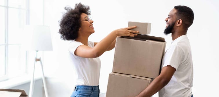 Happy Black Spouses Packing Boxes For Moving, Relocating To New Apartment Standing At Home. Real Estate Rent, Mortgage And Ownership Concept. Family Preparing To Move House.