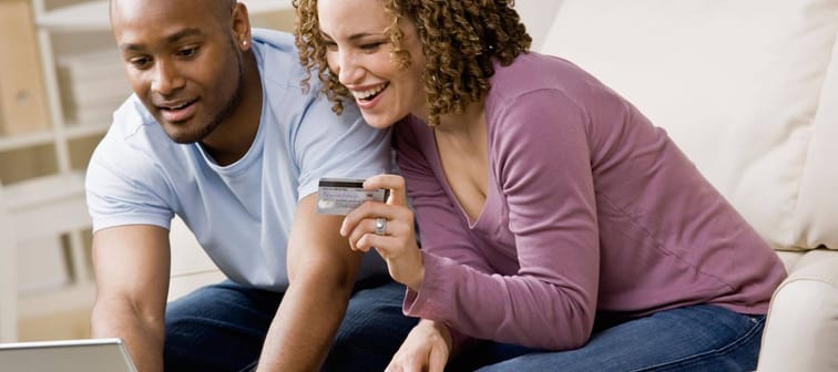 Happy couple using credit card to shop online conveniently