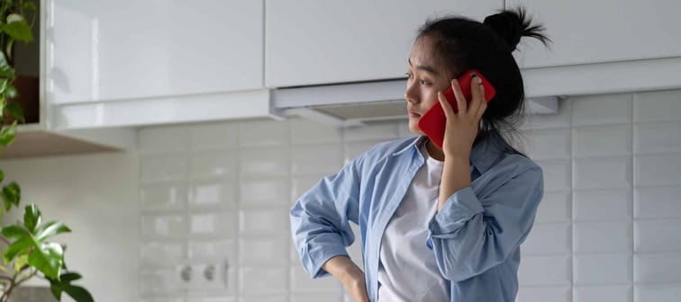 Worried upset Asian woman standing alone in kitchen
