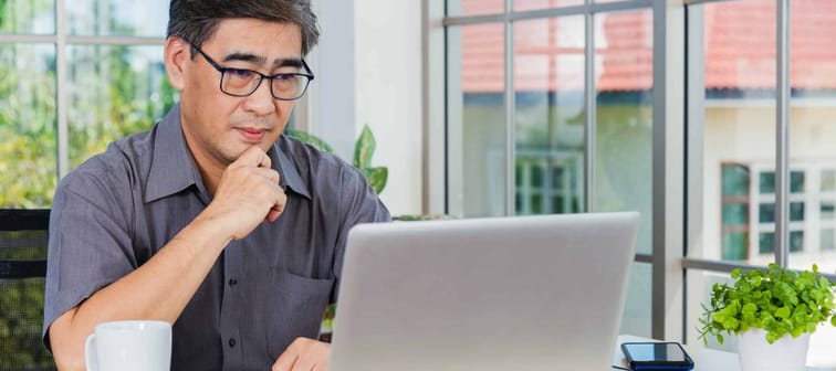 Asian senior business man working online on a modern laptop computer