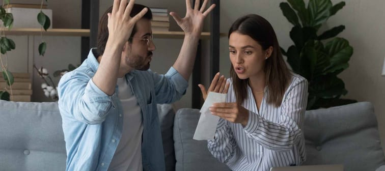 Stressed emotional couple arguing fighting when checking financial papers together finding lack of money on bank account.