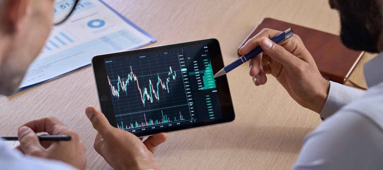 Trader consulting business investor showing trading chart using digital tablet computer analyzing stock exchange market