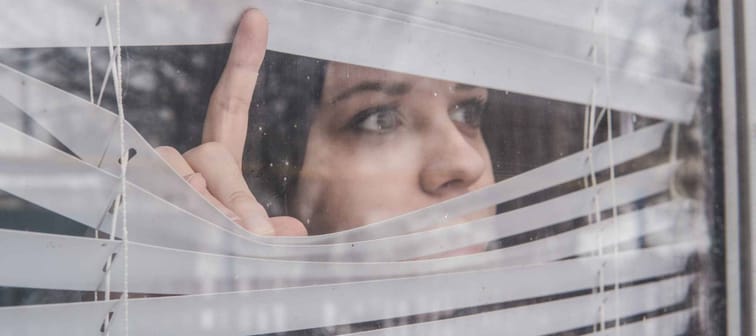 Woman Looking Through the Blinds. Girl looking out the window