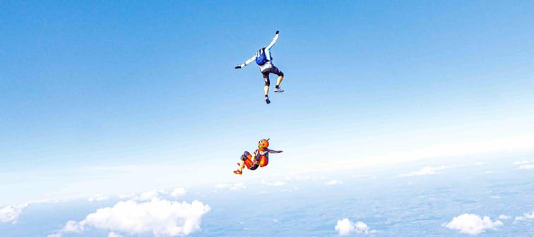 two skydivers in a free fall surrounded by blue sky
