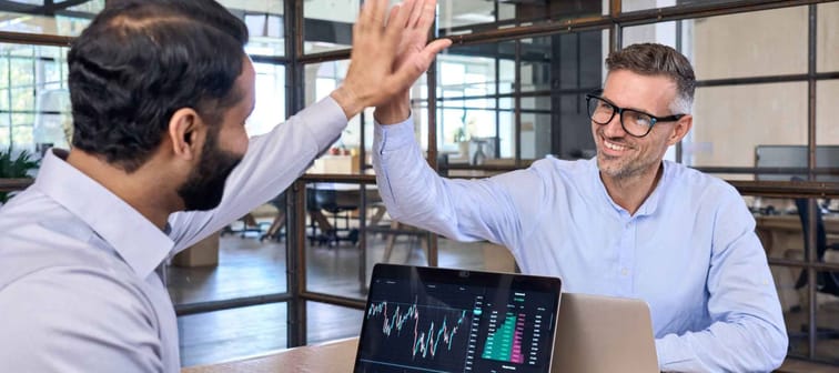 Two happy successful excited diverse traders investors giving high five celebrating successful stock exchange trading deal