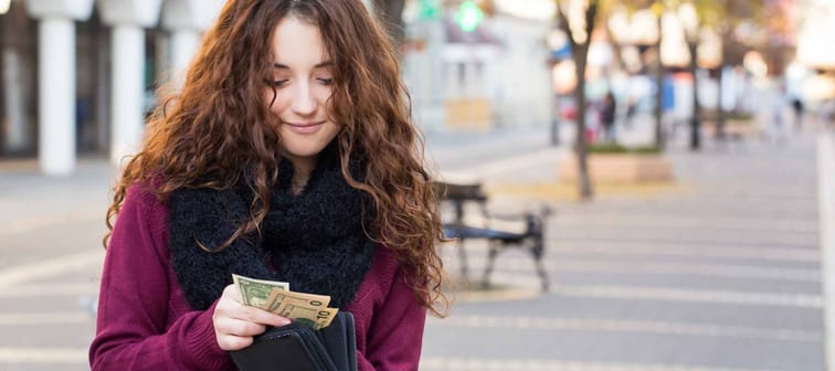 young shopper woman taking out money from wallet on street