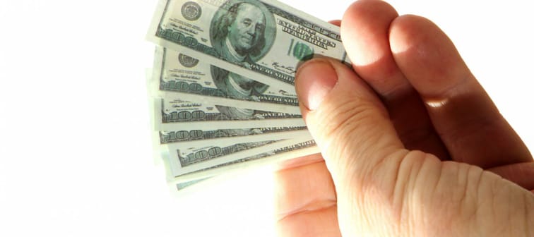 miniature money. small $100.00 dollar bills in a normal mans hands.