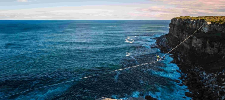 Highlining or Slacklining between two cliffs in the Sydnrey region but ocean, balancing on tight rope