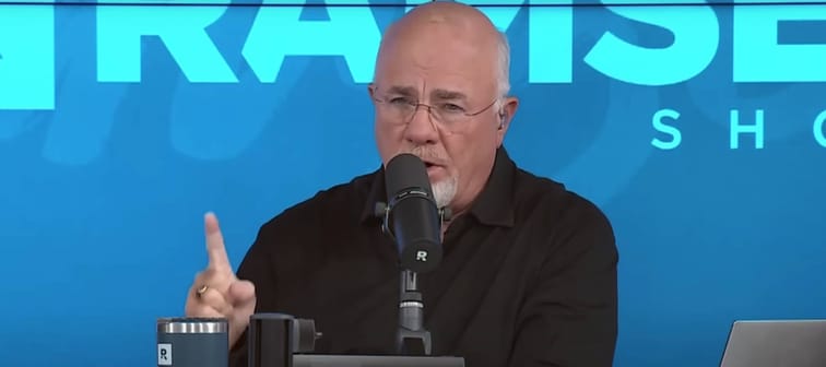 Dave Ramsey sits on the set of his show, talking into a microphone.
