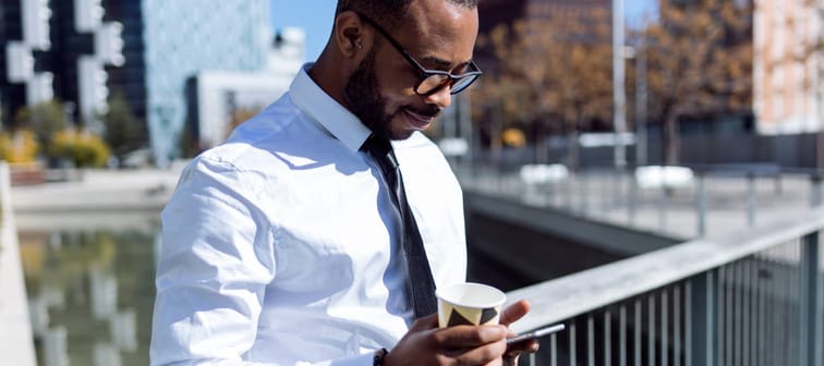 Side view of handsome elegant black man with coffee and phone