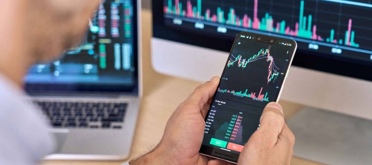 Crypto trader investor broker using smartphone app analyzing financial data