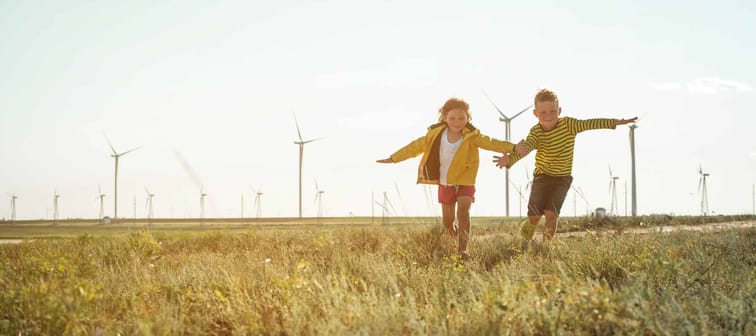 Little girl and boy are running in front of windmills.
