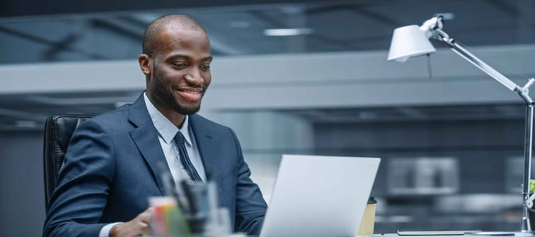 Successful Black Businessman Sitting at Desk Using Laptop