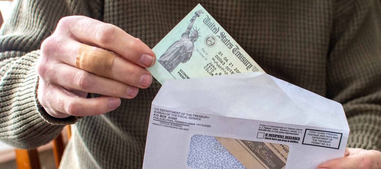 A man's hand holds a letter with a covid aid check from the USA government
