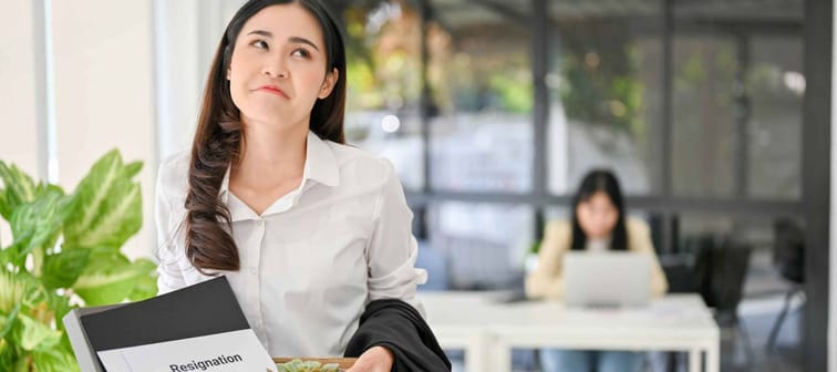Happy and fearless Asian woman carrying her personal stuff and resignation letter