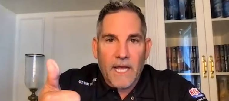 Grant Cardone speaks directly to the camera with hand up in a gesture.