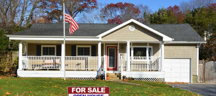 American flag pole Real estate for sale open house welcome sign Suburban Ranch style home with porch sunny autumn day residential neighborhood clear blue sky USA